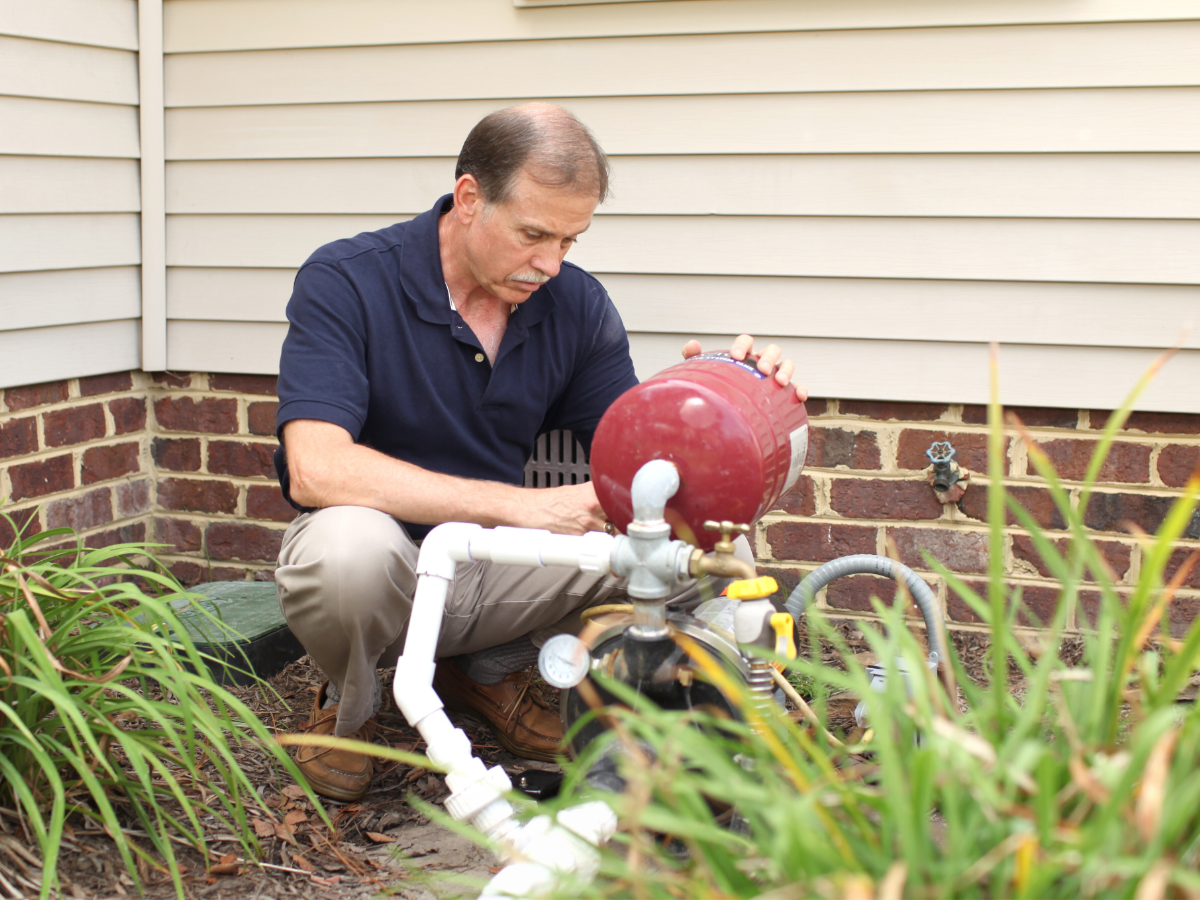 Plumber examining a well pump in homeowner's yard